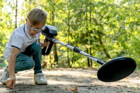 A boy using a metal detector to find loose change.