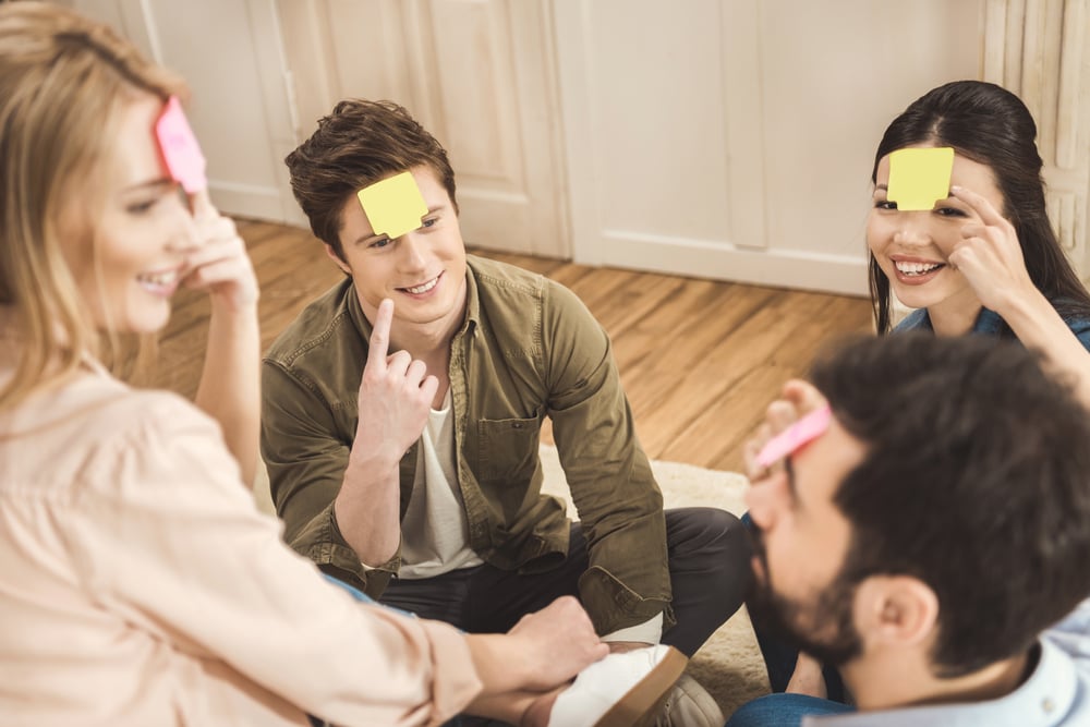 Diverse people playing game guess who and having fun at home