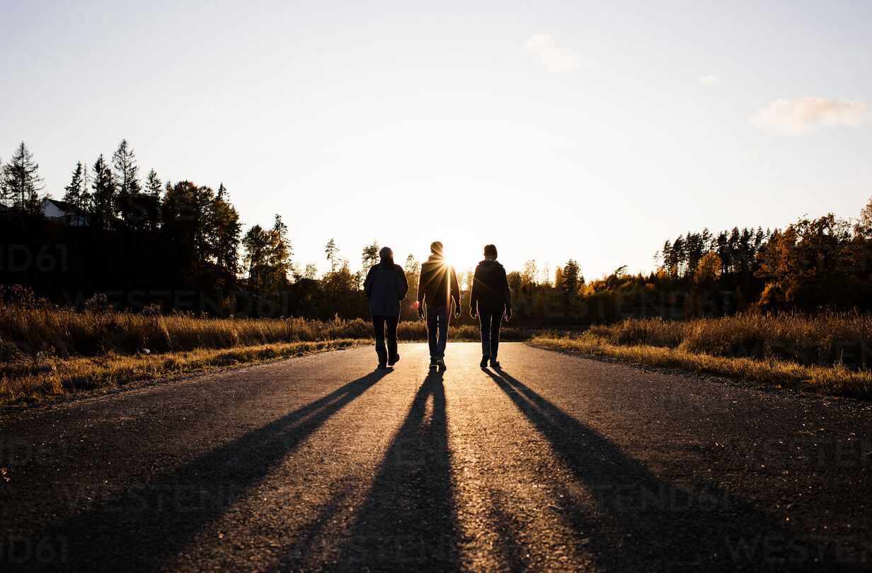 silhouette-of-family-walking-down-a-country-road-at-sunset